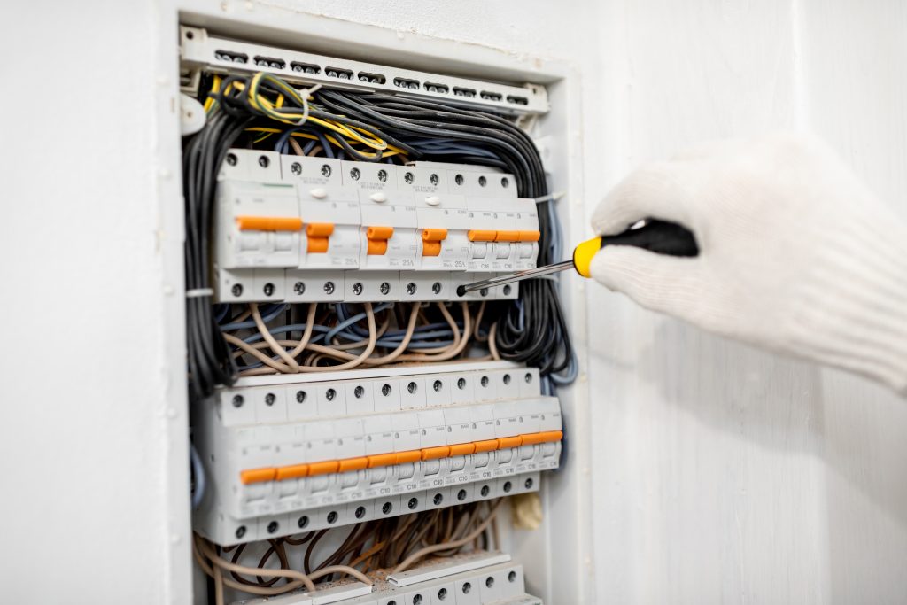Electrician installing or repairing apartment electrical panel, close-up view