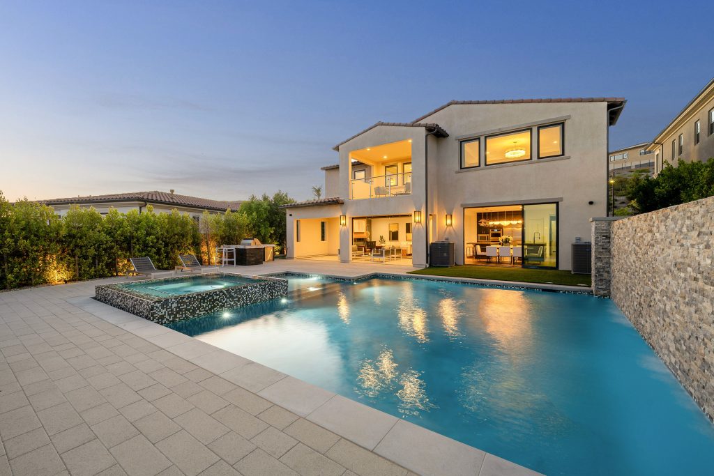 Modern luxury house with a swimming pool and outdoor seating area during twilight.